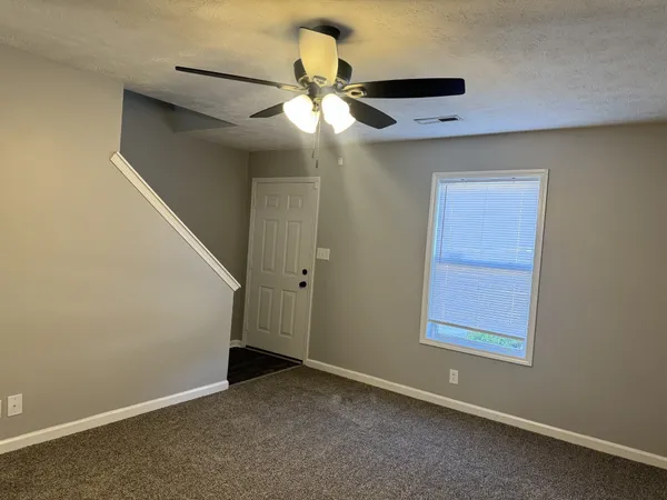 an empty room with windows and fan