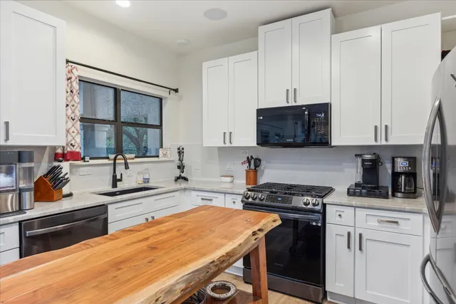 a kitchen with stainless steel appliances granite countertop a stove a sink and a microwave