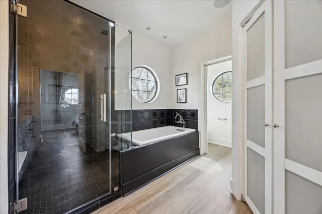 a bathroom with a tub a mirror and a shower