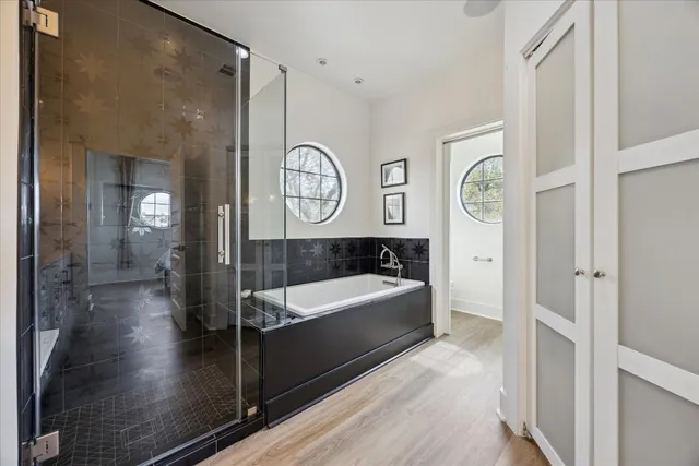 a bathroom with a tub a mirror and a shower