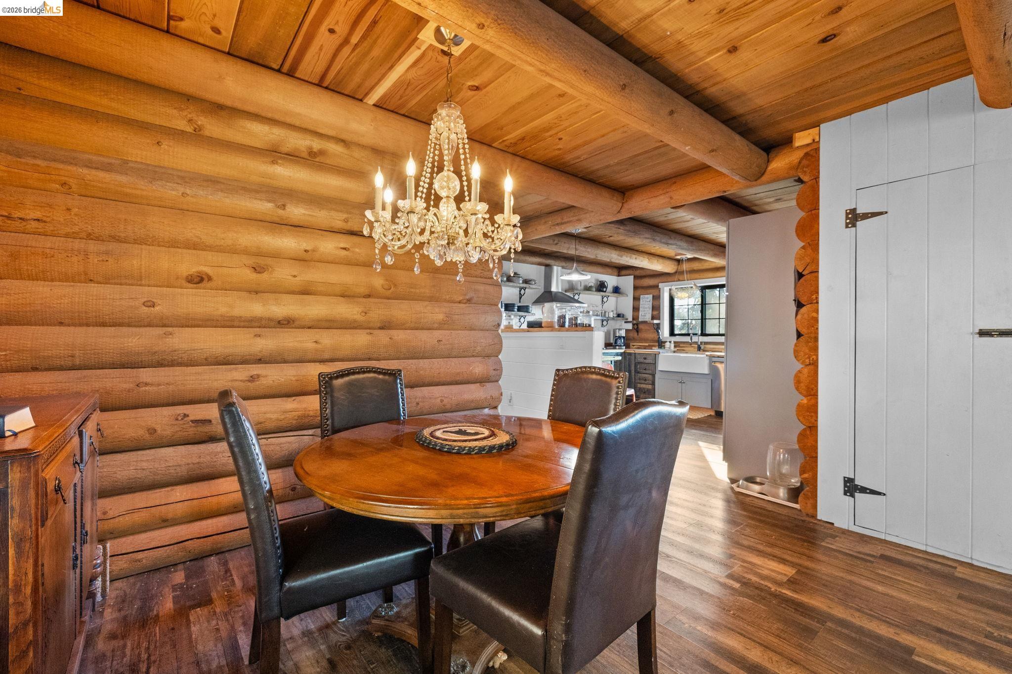 16144 Big Hill Road Sonora, CA 95370 - Photo 14 of 51 Dining area featuring log walls, exposed log ceiling beams, and wood-finish flooring