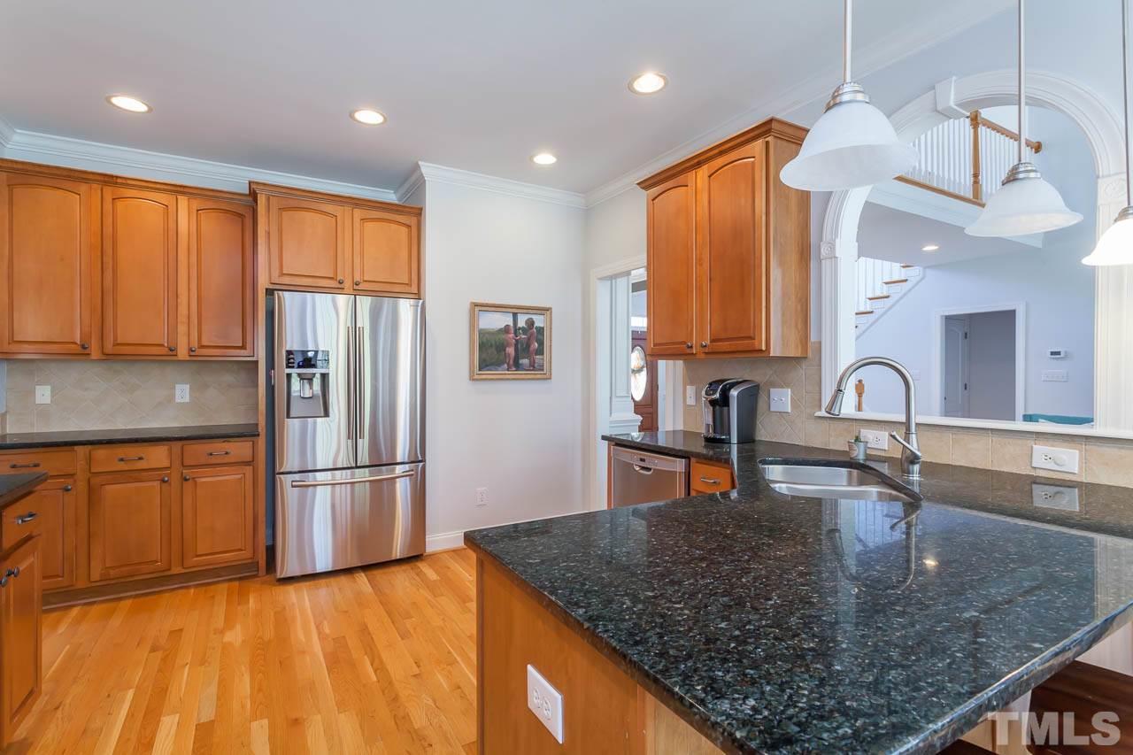 5216 Levering Mill Road Apex, NC 27539 - Photo 8 of 23 a kitchen with stainless steel appliances granite countertop a refrigerator a stove and a sink with wooden floor