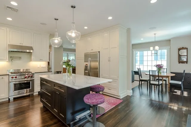 a large kitchen with granite countertop a stove a sink a dining table and chairs