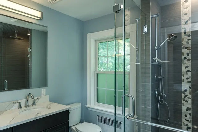 a bathroom with a shower sink vanity and toilet