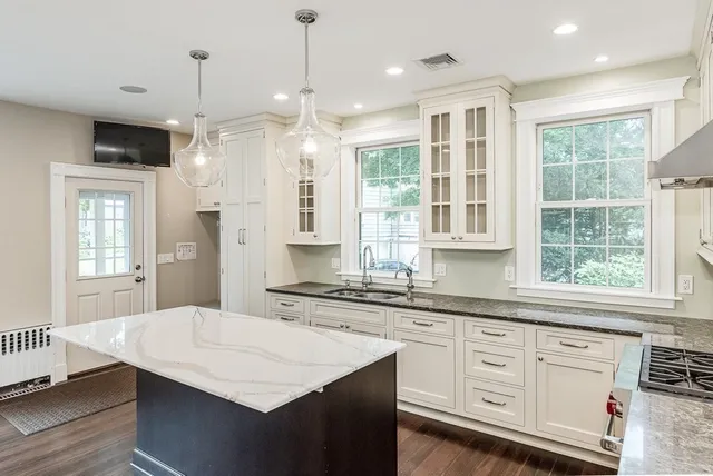 a kitchen with granite countertop a sink a center island stainless steel appliances and cabinets
