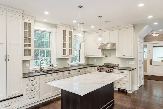 a kitchen with stainless steel appliances granite countertop a sink a stove a refrigerator and island with wooden floor