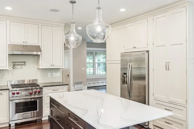 a kitchen with stainless steel appliances a stove a refrigerator and white cabinets