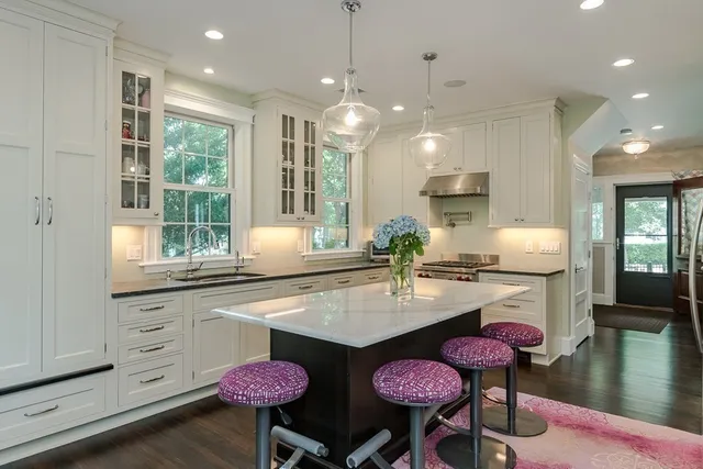 a kitchen with stainless steel appliances kitchen island granite countertop a stove a sink and white cabinets with wooden floor