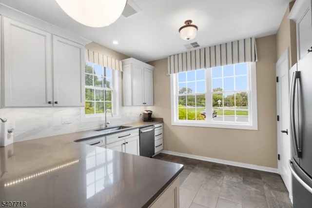 a kitchen with stainless steel appliances granite countertop a sink a window and a counter space