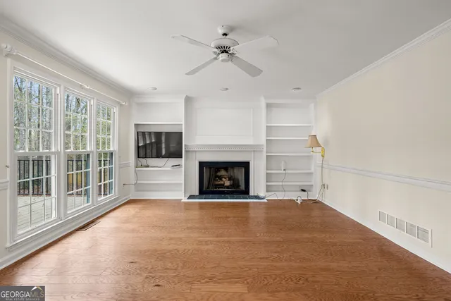 a view of a livingroom with a fireplace a ceiling fan and windows