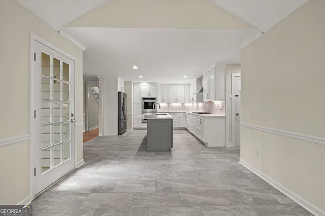 a dining hall with stainless steel appliances granite countertop a refrigerator and a sink