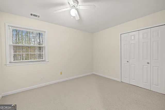 an empty room with a chandelier fan and closet area