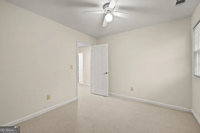 an empty room with a window and a fan