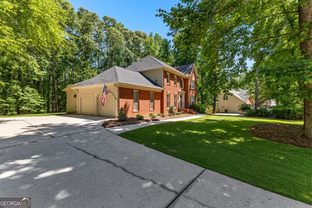 a view of a house with a big yard and large trees