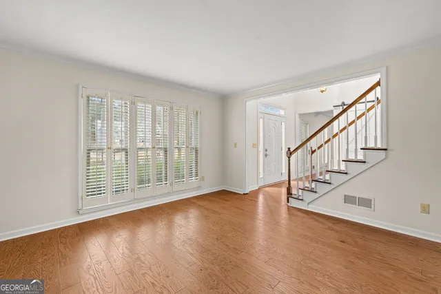 a view of an empty room with wooden floor and a window