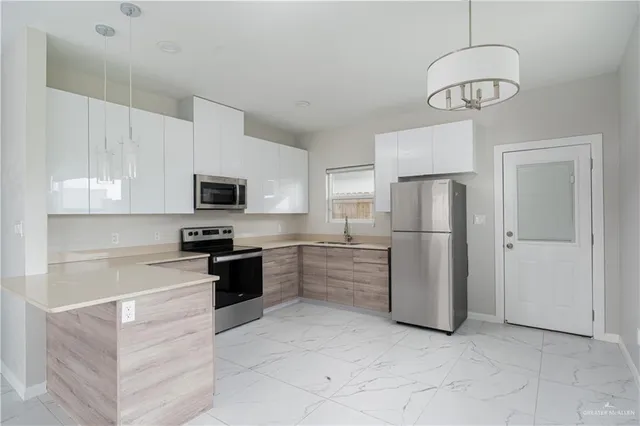 a kitchen with stainless steel appliances granite countertop a refrigerator a stove a sink and a microwave