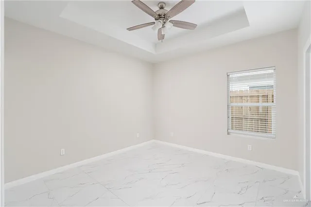 an empty room with a chandelier fan and windows