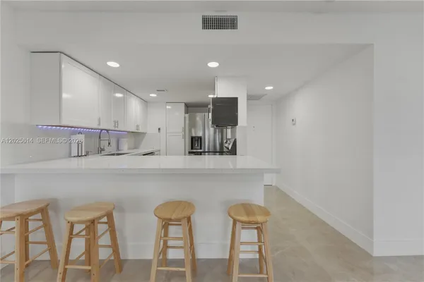 a kitchen with white cabinets and chairs