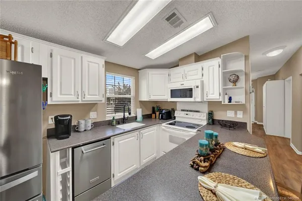 a kitchen with stainless steel appliances granite countertop a refrigerator sink stove microwave and cabinets