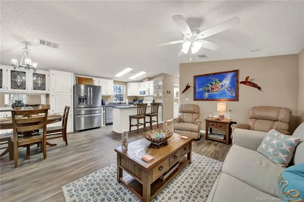 a living room with furniture kitchen view and a chandelier