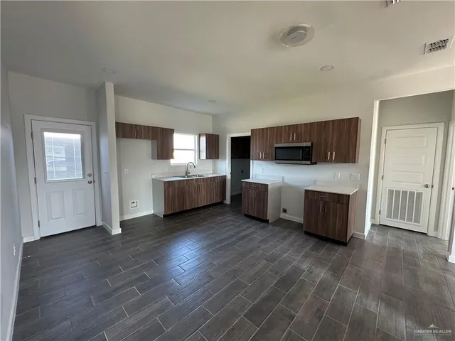 a large white kitchen with stainless steel appliances wooden floors and large window