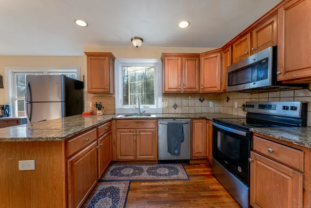 a kitchen with stainless steel appliances granite countertop a sink stove microwave and refrigerator