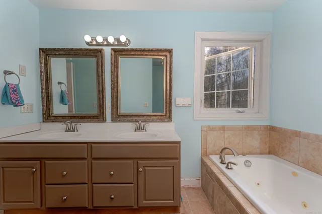 a bathroom with a tub sink and mirror