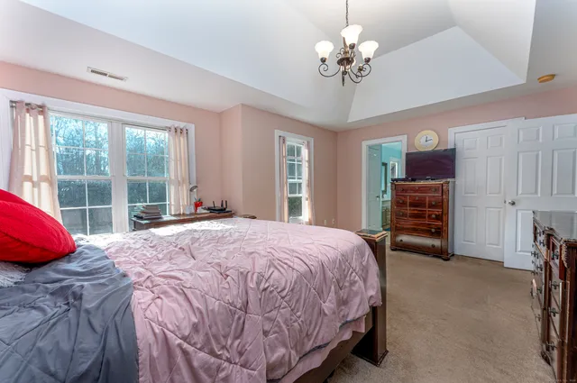 a spacious bedroom with a bed and a chandelier