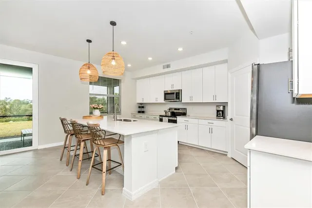 a kitchen with stainless steel appliances kitchen island granite countertop a dining table chairs sink and cabinets