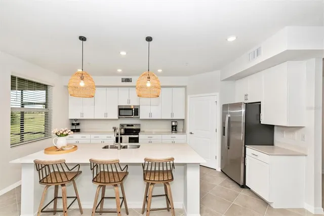 a kitchen with stainless steel appliances kitchen island granite countertop a sink a stove a dining table and chairs