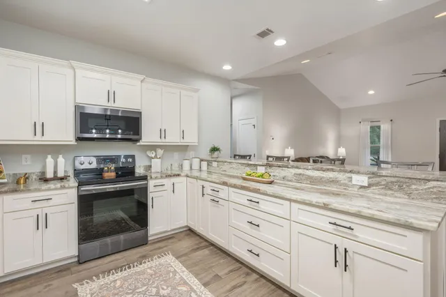 a kitchen with granite countertop white cabinets and a window