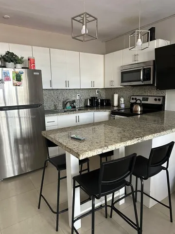 a kitchen with stainless steel appliances granite countertop a dining table chairs microwave and sink