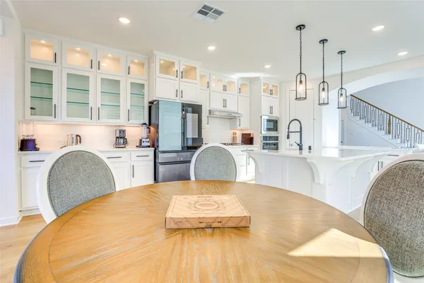 a kitchen with stainless steel appliances granite countertop a stove a sink dishwasher a dining table and chairs with wooden floor