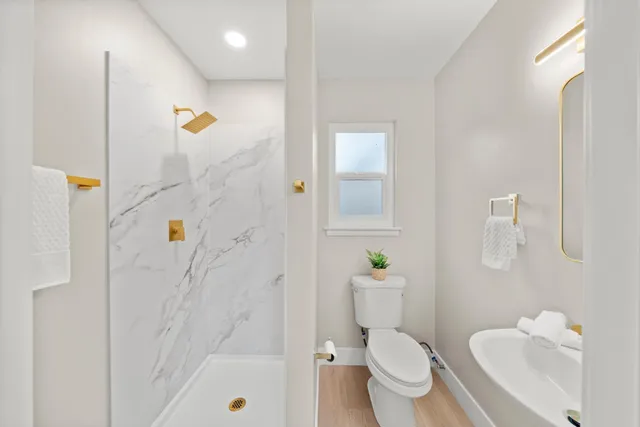 a bathroom with a sink a toilet and shower