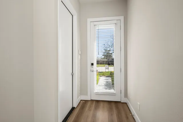 a view of an empty room with wooden floor and a window