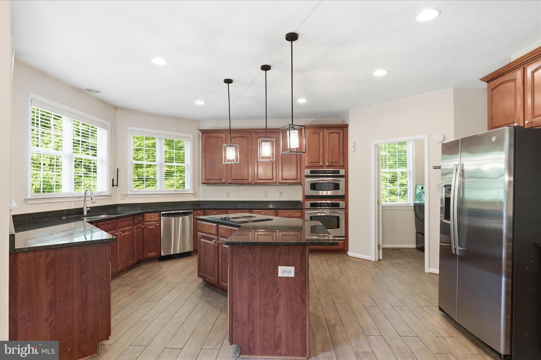 5829 Lockmere Place Waldorf, MD 20601 - Photo 17 of 54 a kitchen with stainless steel appliances granite countertop a refrigerator a sink dishwasher a stove and a dining table with wooden floor