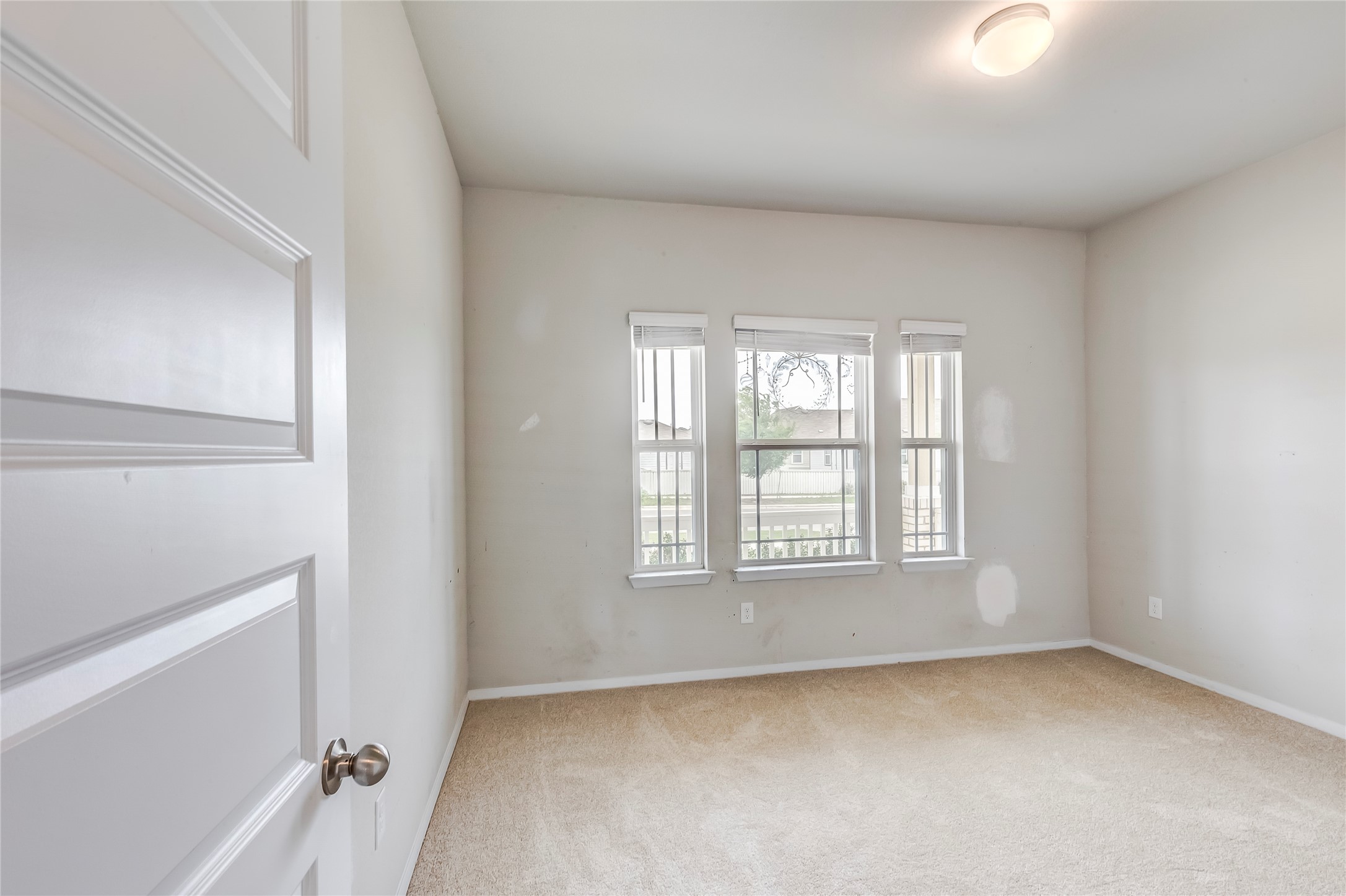 2721 Winding Creek Road Kyle, TX 78640 - Photo 21 of 27 Neutral-toned carpeted room with multiple windows and a flush-mount ceiling light fixture