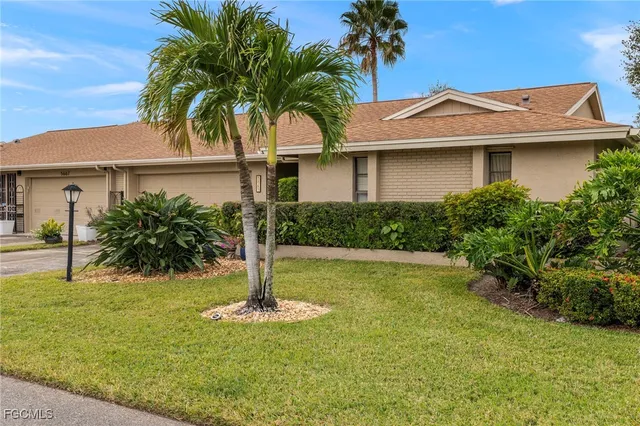 a front view of a house with yard and palm tree
