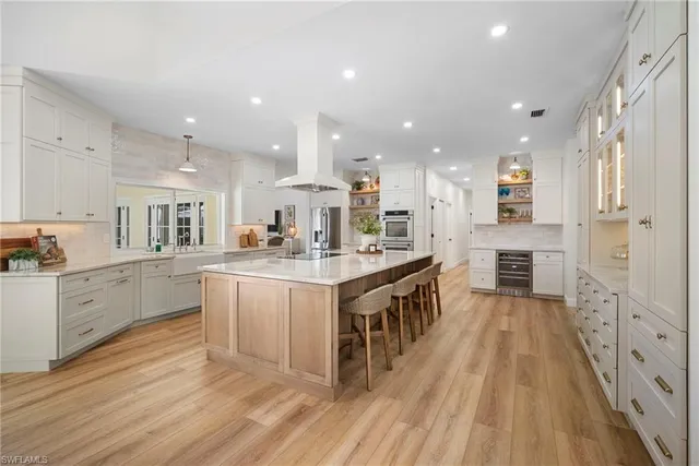 a large kitchen with kitchen island wooden floors granite counter tops and white cabinets