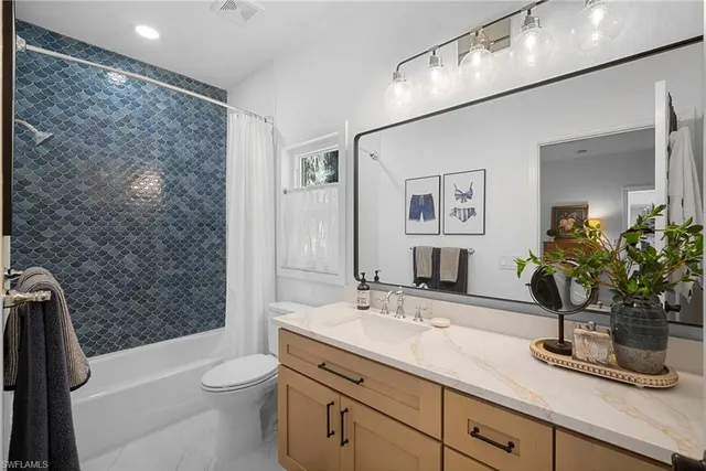 a bathroom with a granite countertop sink a toilet a mirror and shower