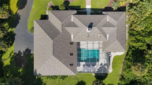 an aerial view of a house with swimming pool and large trees