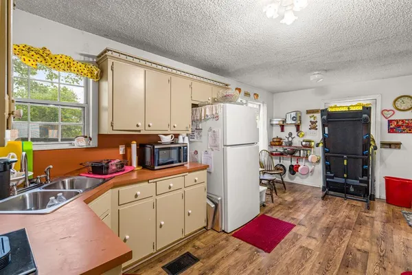 a kitchen with a refrigerator a stove top oven a sink and dishwasher with wooden floor