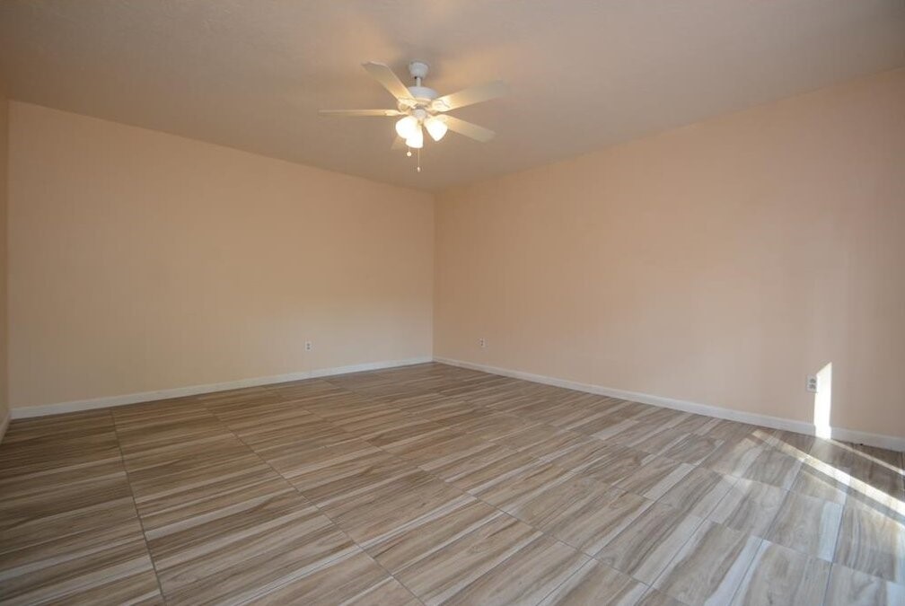 15 South Tallowberry Drive Spring, TX 77381 - Photo 14 of 26 Spacious, bright room with neutral walls, sleek tile flooring, and a ceiling fan for a versatile living space.