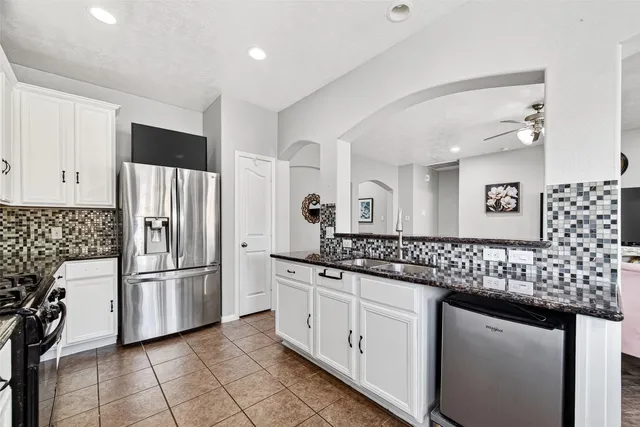 a kitchen with stainless steel appliances kitchen island granite countertop a stove top oven a sink a dining table and chairs with white cabinets