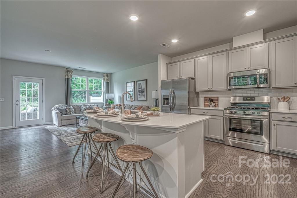 902 Pk Bnd Trail, Unit 72 Tega Cay, SC 29708 - Photo 4 of 13 a kitchen with kitchen island a stove a table and chairs in it