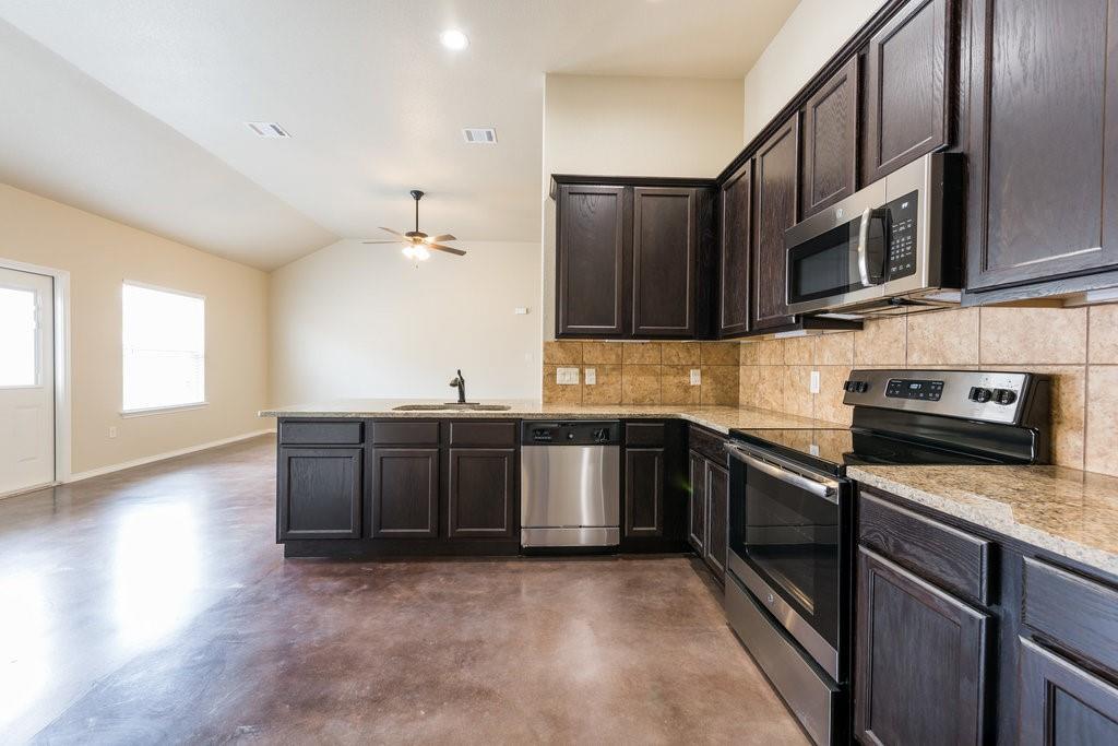 491 Jack Rabbit Lane, Unit A Buda, TX 78610 - Photo 3 of 22 A well-appointed kitchen features dark wood cabinetry, granite countertops, and modern stainless steel appliances.