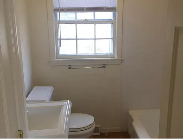 a white toilet sitting in a bathroom next to a window