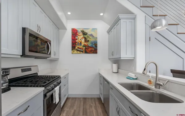 a kitchen with stainless steel appliances a sink a stove top oven a refrigerator and dishwasher