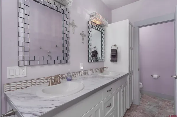 a bathroom with a granite countertop double vanity sink and mirror