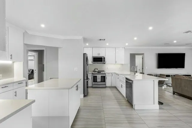 a large white kitchen with stainless steel appliances and cabinets